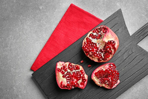 Houten plank met rijpe granaatappel op grijze achtergrond — Stockfoto