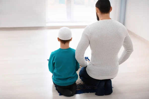 Islamitische vader en zoon bidden samen, binnenshuis — Stockfoto