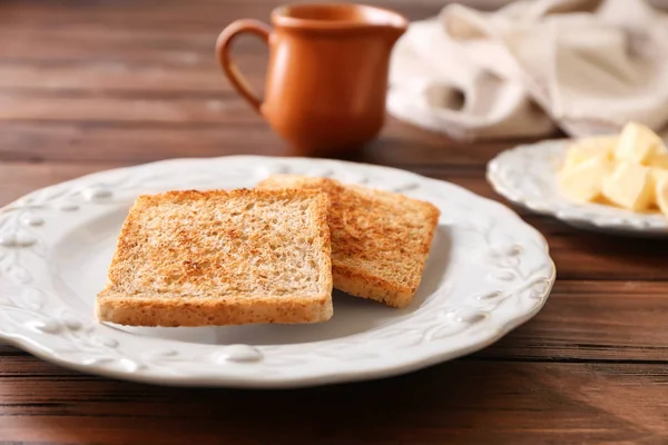 Prato com saboroso pão torrado na mesa de madeira — Fotografia de Stock
