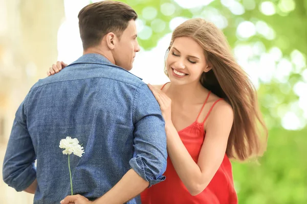 Homem apresentando flor para namorada ao ar livre — Fotografia de Stock