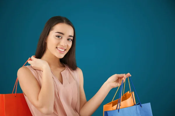 Mulher bonita com sacos de compras no fundo de cor — Fotografia de Stock