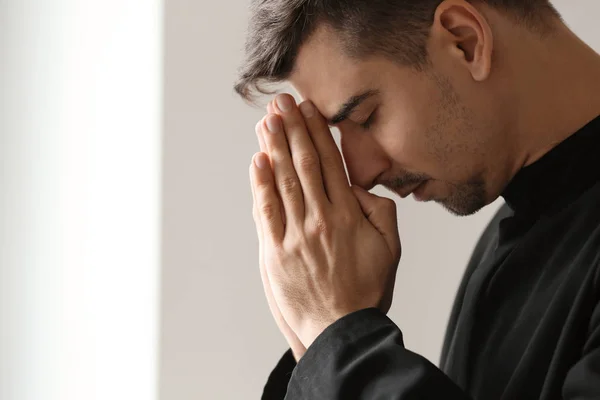 Young priest praying to God indoors — Stock Photo, Image