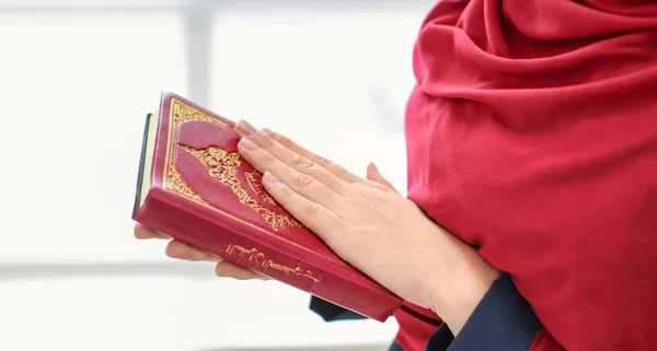 コーランを押しながら祈っていると 室内の若いイスラム教徒の女性 — ストック写真