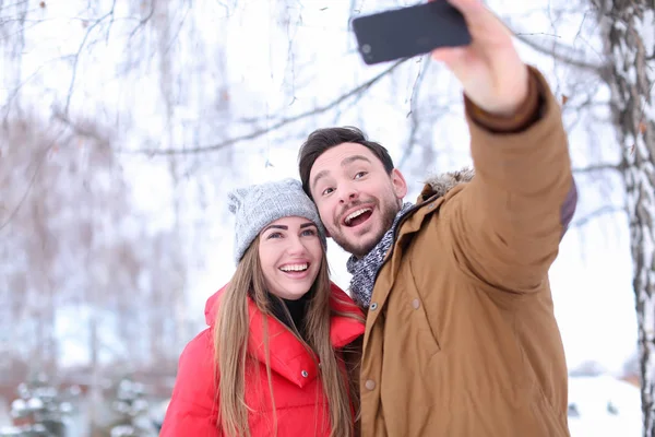 Ungt par tar selfie i snöig park på vintersemester — Stockfoto