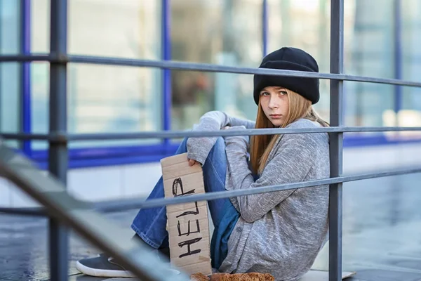 Sin hogar pobre adolescente sosteniendo pedazo de cartón con la palabra AYUDA al aire libre —  Fotos de Stock