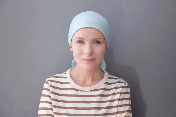 Молода жінка з раком голови на сірому фоні — стокове фото