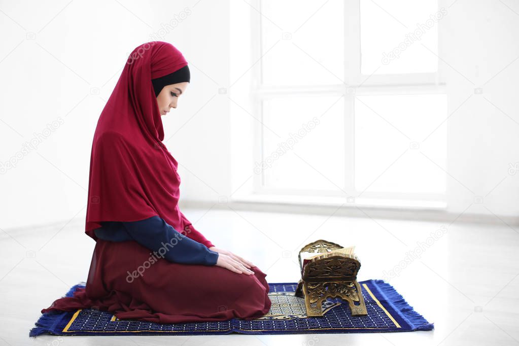 Young Muslim woman reading Koran, indoors