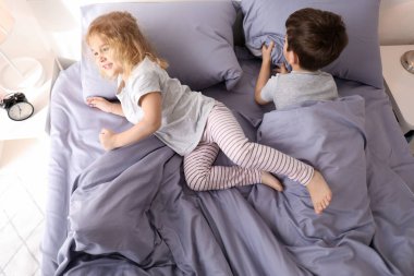 Sevimli küçük çocuklar evde yatakta uyumaya çalışıyor. Aile yatmadan