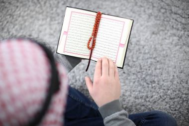 Genç Müslüman erkek Kur'an, kapalı okuma