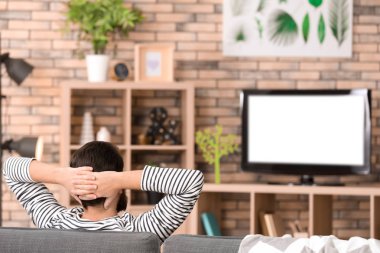 Adam evde koltukta istirahat ederken TV izlerken