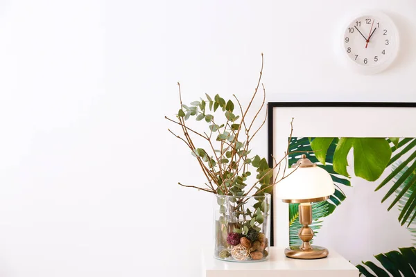 Elegant lampa och glas vas med grenar på bord inomhus — Stockfoto