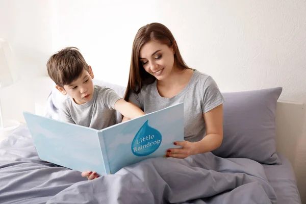 Ibu dan anaknya membaca buku di tempat tidur di ruang anak-anak — Stok Foto