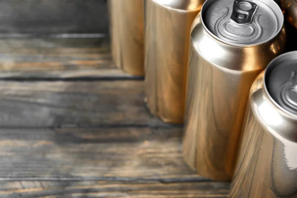 Cans of beer on wooden background, closeup