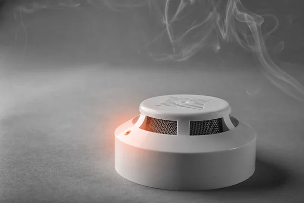 Detector de humo con luz de advertencia sobre fondo gris —  Fotos de Stock