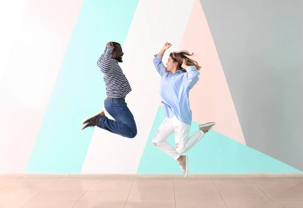 Grazioso interrazziale coppia jumping contro colore parete — Foto Stock