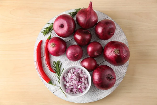 Wooden board with ripe red onions and chili peppers on light background — Stock Photo, Image