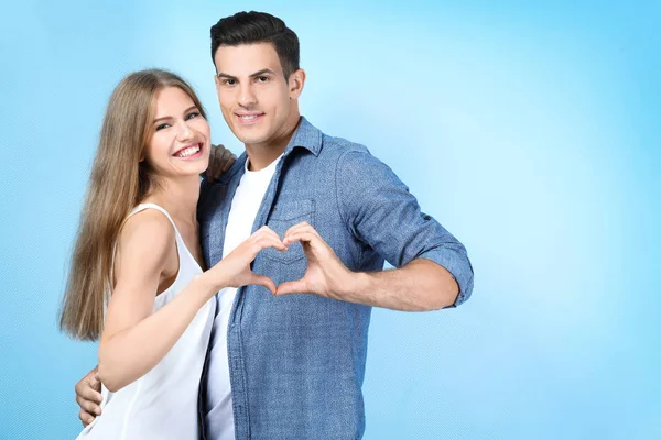 Young couple holding hands in shape of heart on light background — Stock Photo, Image