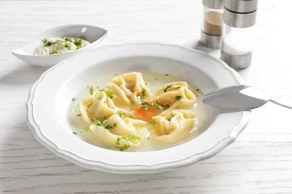 Smakelijk bouillon met knoedels op houten tafel — Stockfoto