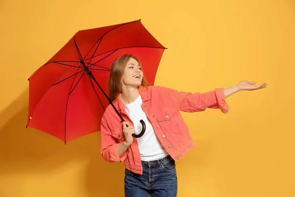 Giovane donna con ombrello rosso su sfondo a colori — Foto Stock