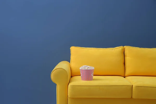 Wygodna sofa z popcorn dla kina domowego na kolor tła. Oglądając film — Zdjęcie stockowe