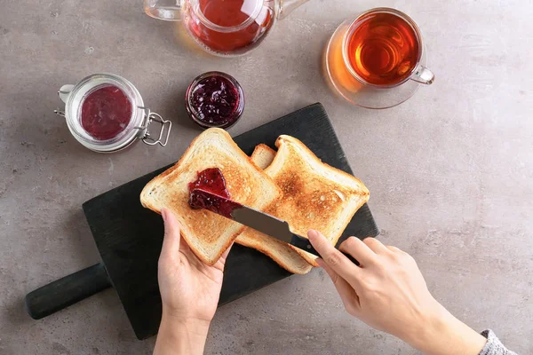 Wanita menyebarkan selai manis di atas meja roti panggang, pemandangan atas — Stok Foto