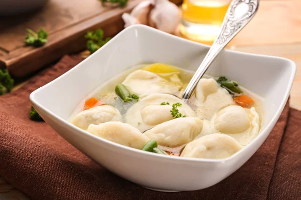 Tigela com caldo saboroso e bolinhos na mesa — Fotografia de Stock