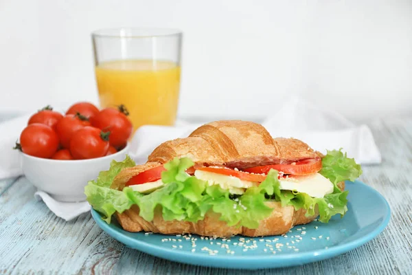 Plaat met heerlijke croissant sandwich op houten tafel — Stockfoto