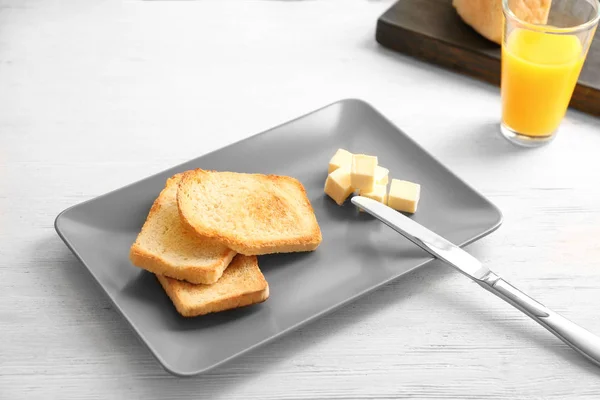 Prato com saboroso pão torrado e manteiga na mesa de madeira — Fotografia de Stock