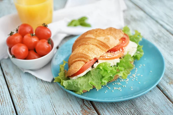 Plaat met heerlijke croissant sandwich op houten tafel — Stockfoto
