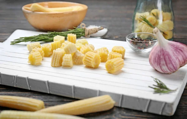 White cutting board with fresh young baby corn on table, closeup — Stock Photo, Image