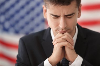 Genç adam Amerika için dua uygun ve arka plan üzerinde bayrak