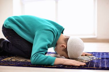Little Muslim boy praying, indoors clipart