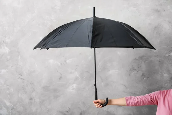 Mujer sosteniendo paraguas negro sobre fondo gris — Foto de Stock