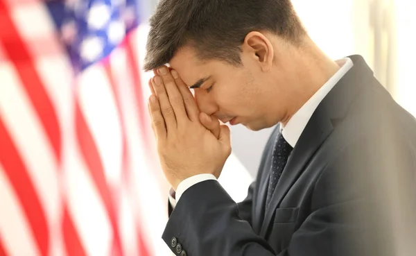 Jongeman bidden in de buurt van Amerikaanse vlag — Stockfoto