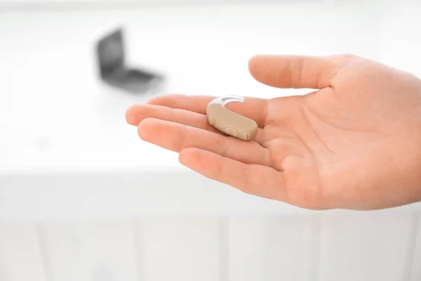 Man holding hearing aid on light background, closeup — Stock Photo, Image