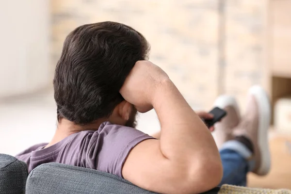 Man Tv kijken tijdens het rusten op de sofa thuis — Stockfoto