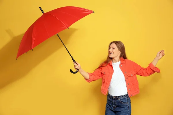 Giovane donna con ombrello rosso su sfondo a colori — Foto Stock