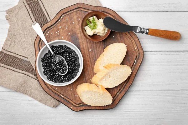 Черная икра подается с хлебом и маслом на деревянной доске — стоковое фото