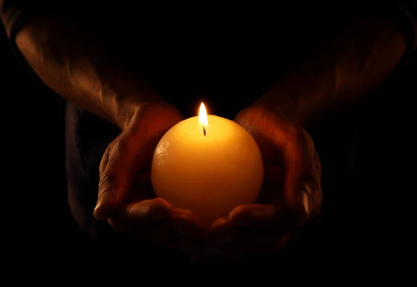 Jovem segurando vela acesa na escuridão — Fotografia de Stock