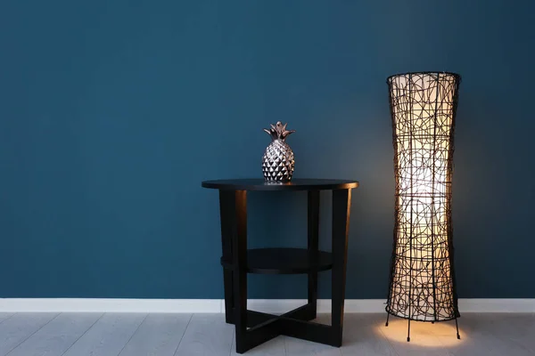 Lámpara de pie con mesa cerca de pared de color —  Fotos de Stock
