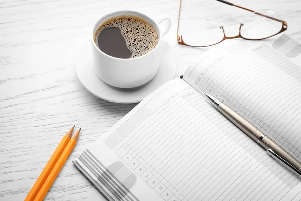 Notebook and cup of coffee on table — Stock Photo, Image