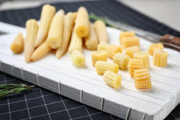 White cutting board with fresh young baby corn on table, closeup — Stock Photo, Image