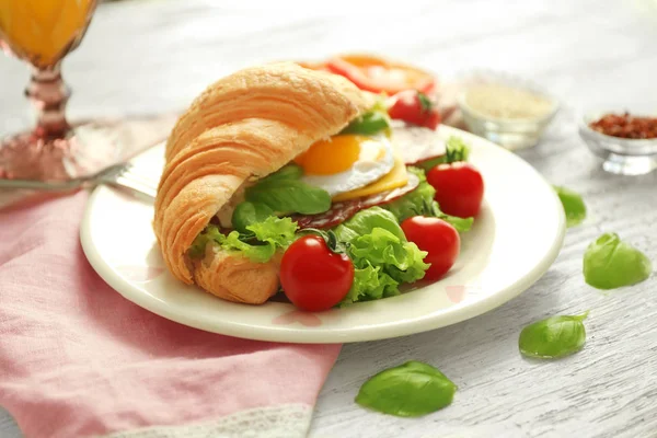 Placa com saboroso sanduíche croissant na mesa — Fotografia de Stock