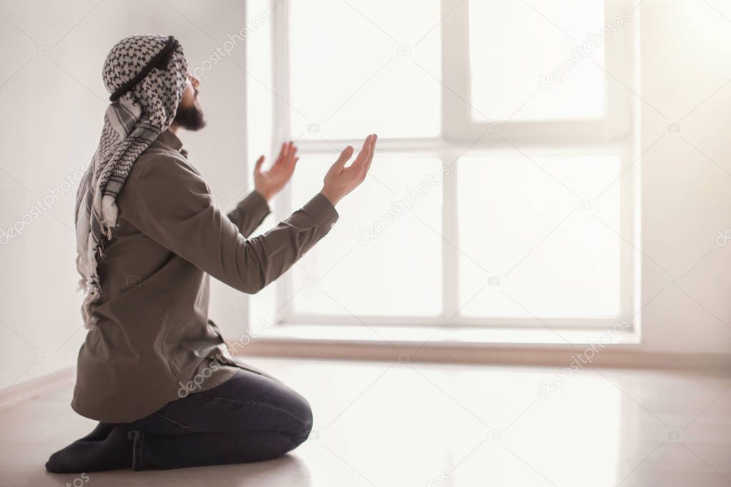 Young Muslim man praying, indoors