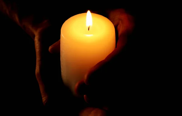 Junger Mann mit brennender Kerze in der Dunkelheit — Stockfoto