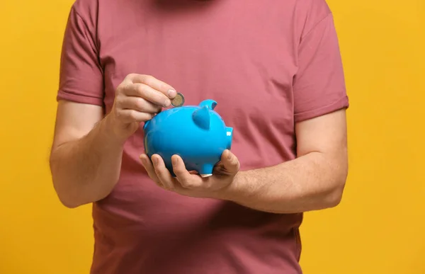 Senior man munt ingebruikneming piggy bank op kleur achtergrond — Stockfoto