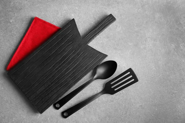 Wooden board, spatula and spoon on grey background. Cooking utensils