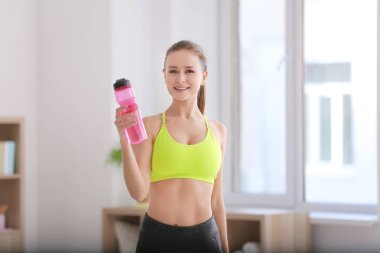 Güzel genç kadın fitness egzersizleri evde yaptıktan sonra su şişe