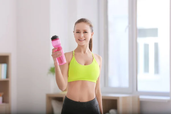 Krásná mladá žena s lahví vody po tom fitness cvičení doma — Stock fotografie