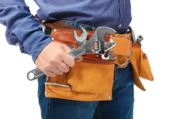 Plumber with tool belt and wrench on white background, closeup — Stock Photo, Image